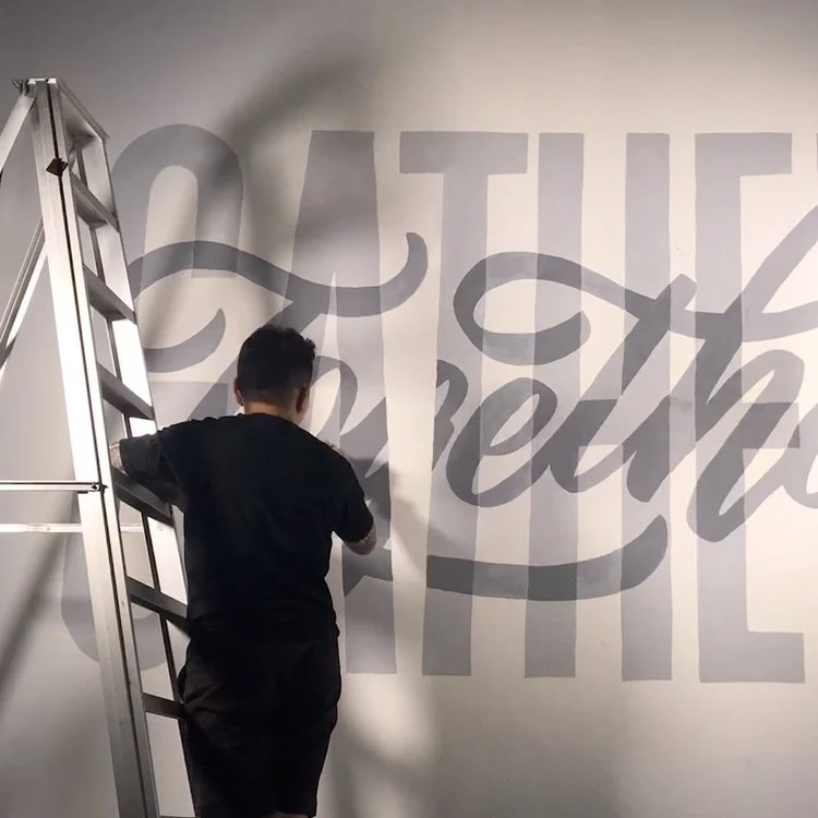 EJ painting a large Gather Together wall mural