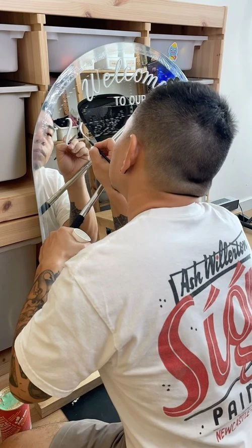 EJ painting welcoming lettering onto a round mirror